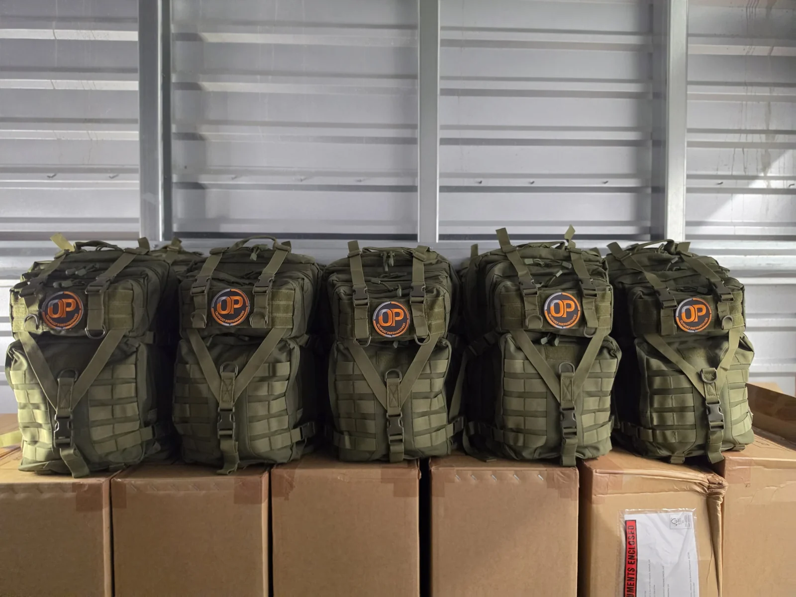 A row of finished Outpost go-bags on shipping boxes, patches forward