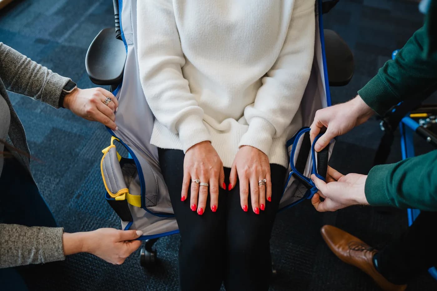 A ProMove transfer sling being fitted to a seated person by two staff
