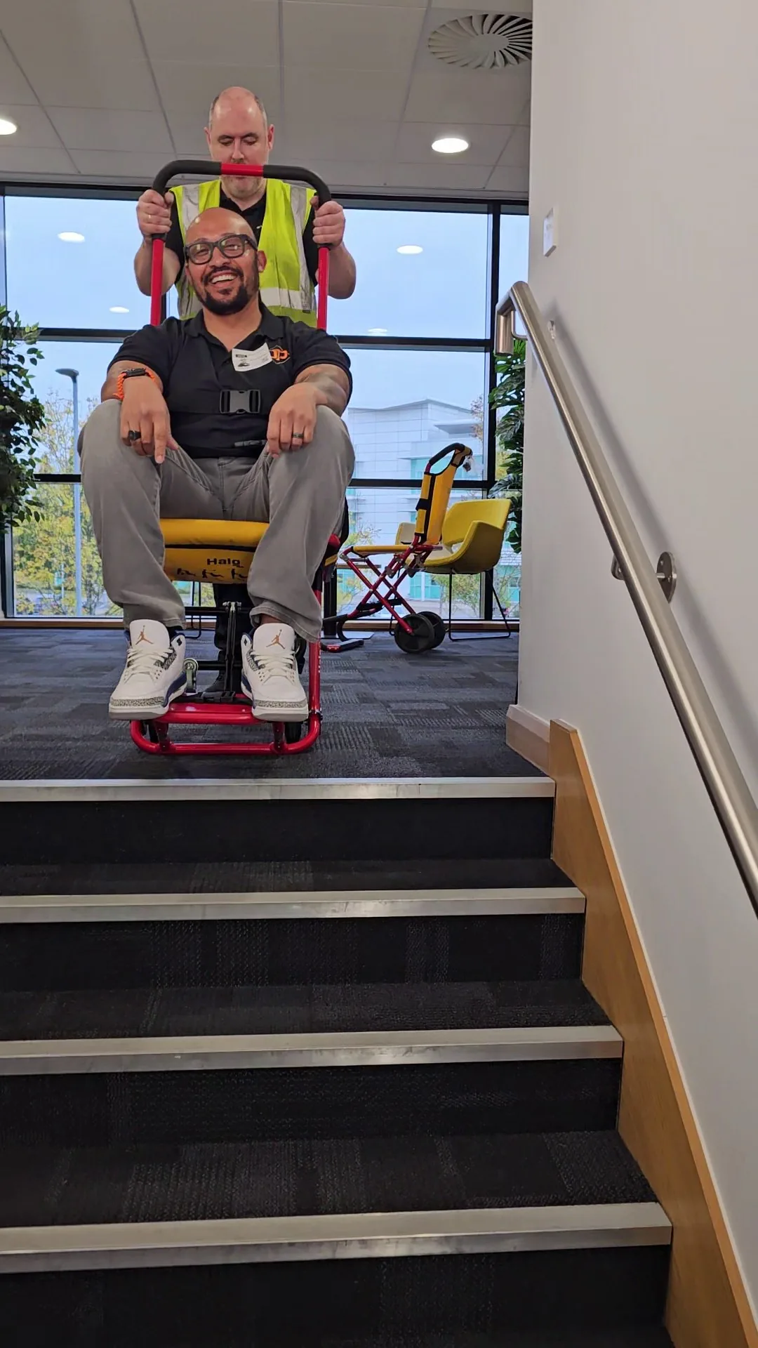 A HALO evacuation chair at the base of an open staircase in a public building