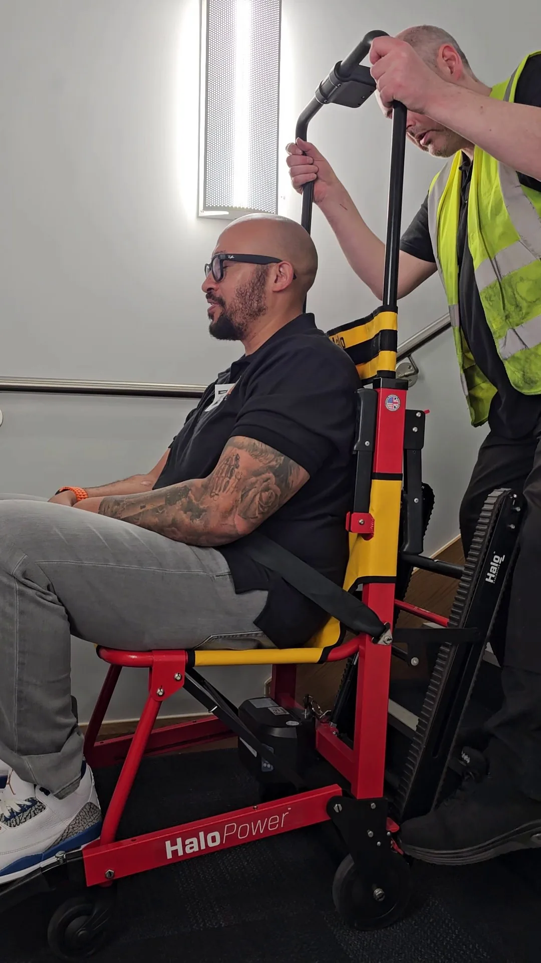 A student seated in a HALO Power evacuation chair at the foot of a staircase