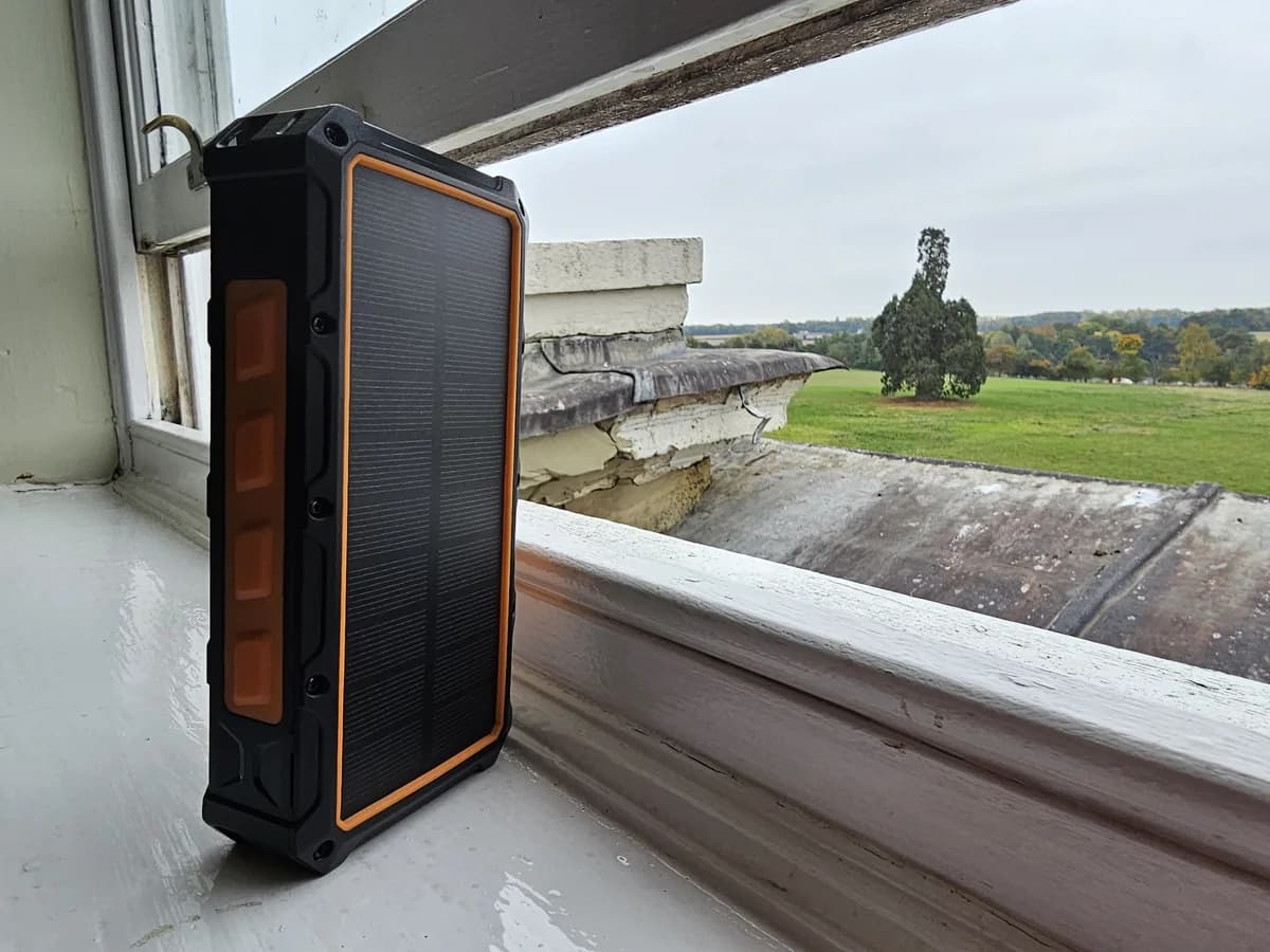 A rugged solar power bank charging on a windowsill